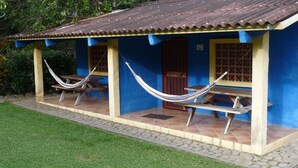 A small, single-story building with a corrugated metal roof and a blue exterior. There are two hammocks hanging between the wooden beams of the porch, and a small table is visible. - Guicci Resort - Playa Corona beach  (San Carlos)