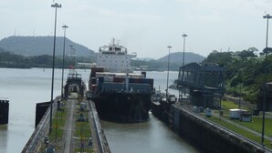 A cargo ship docked at a port with a lock system, surrounded by water and greenery. - Guicci Resort - Playa Corona beach  (San Carlos)