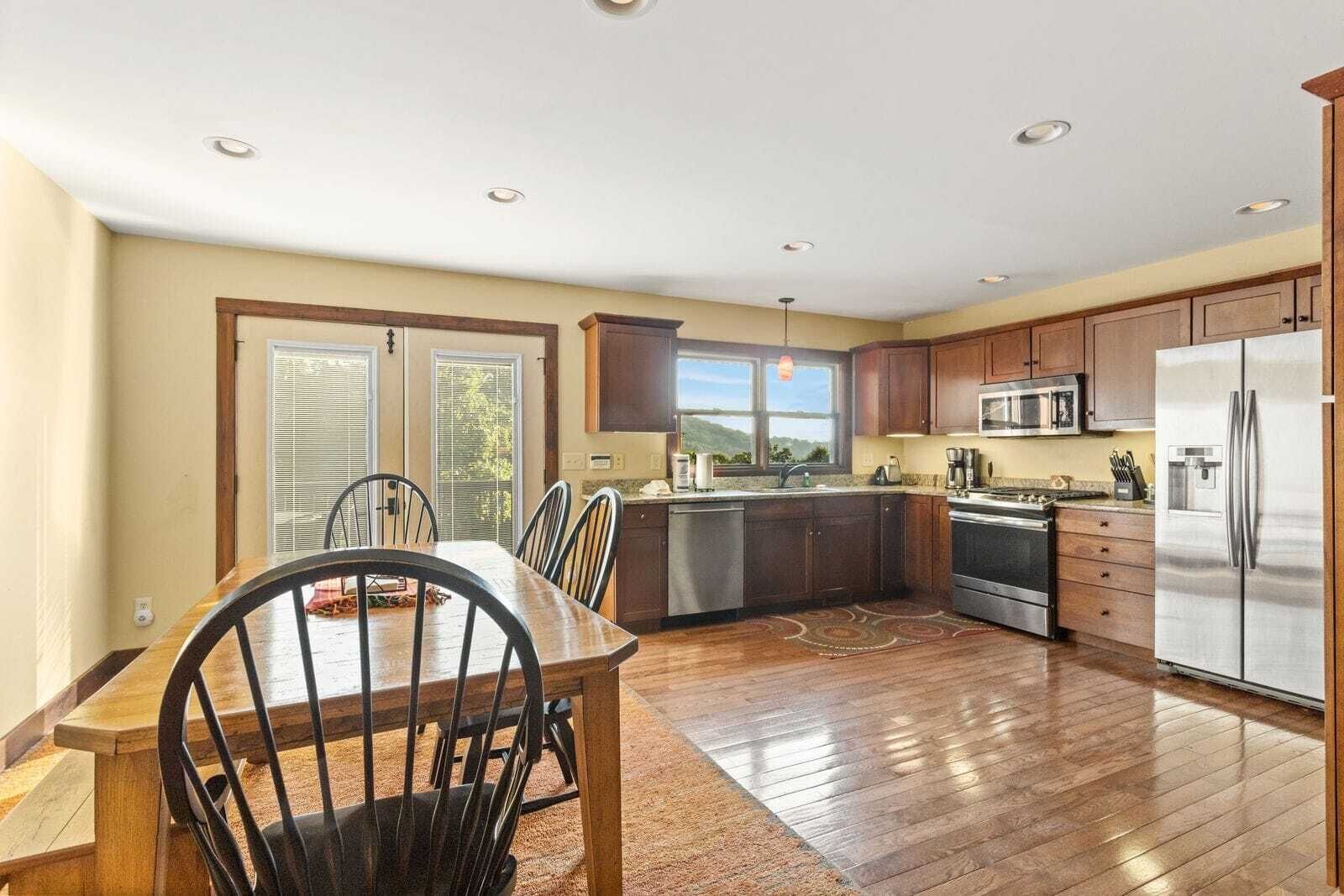 Una cocina amplia con armarios de madera, electrodomésticos de acero inoxidable y un comedor con mesa y sillas.