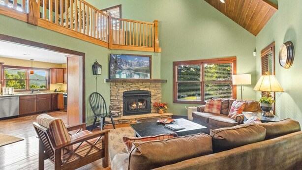 A spacious living area with a fireplace, a high ceiling, and a view of the kitchen. - Mountain Cabin On Quiet Property (Boone)