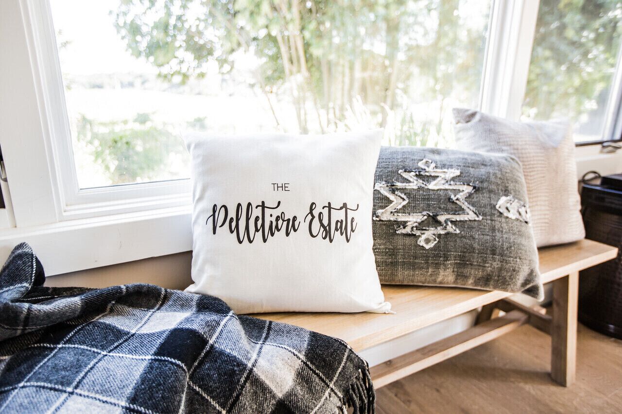 Un banco con dos almohadones decorativos, uno con texto y otro con un diseño.