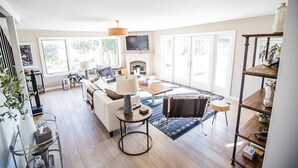 Een ruime woonkamer met een bank, salontafel en een open haard.