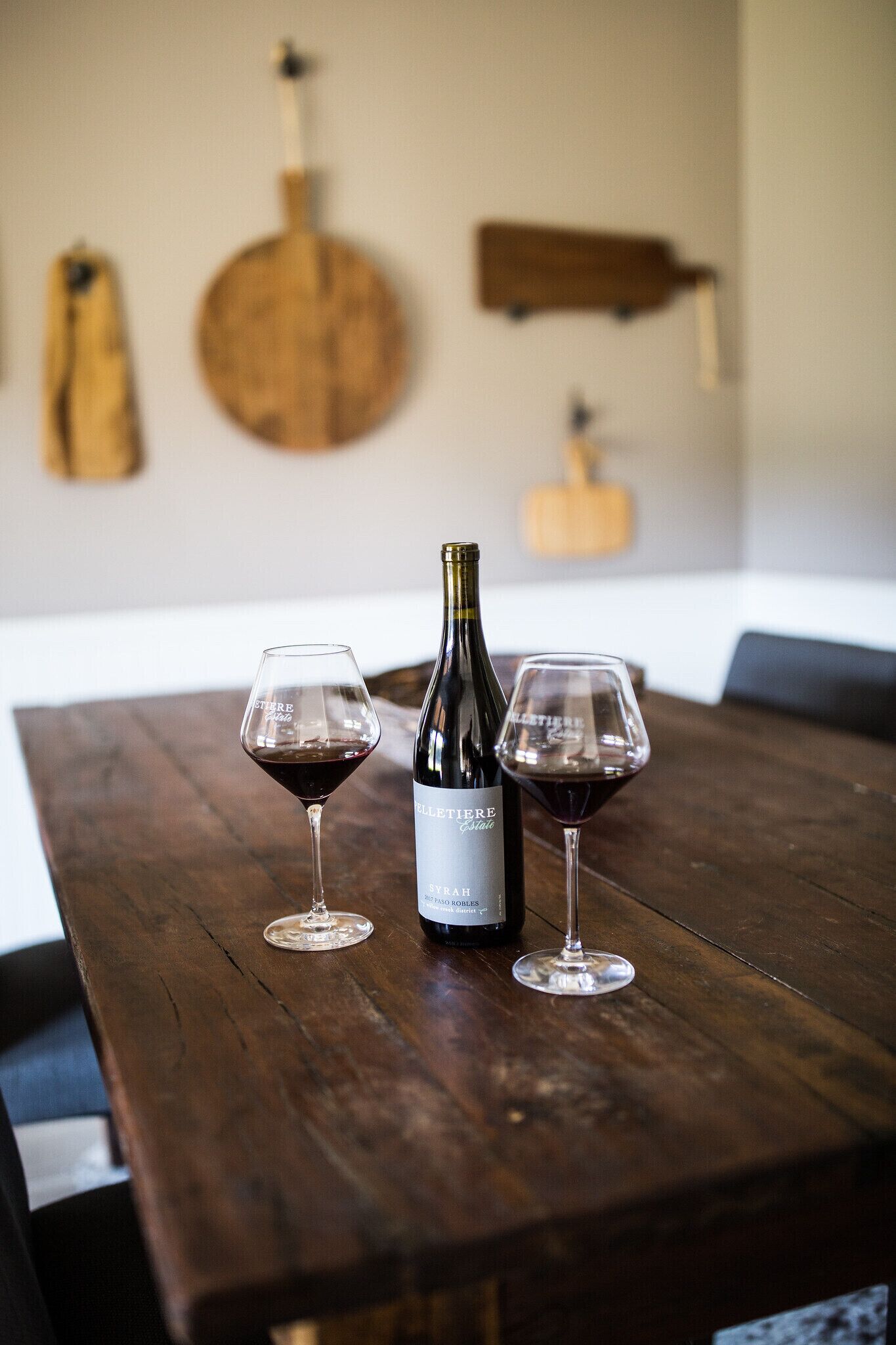 Une table en bois sur laquelle se trouvent une bouteille de vin et deux verres.