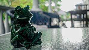 Une figurine de grenouille verte posée sur une surface réfléchissante.