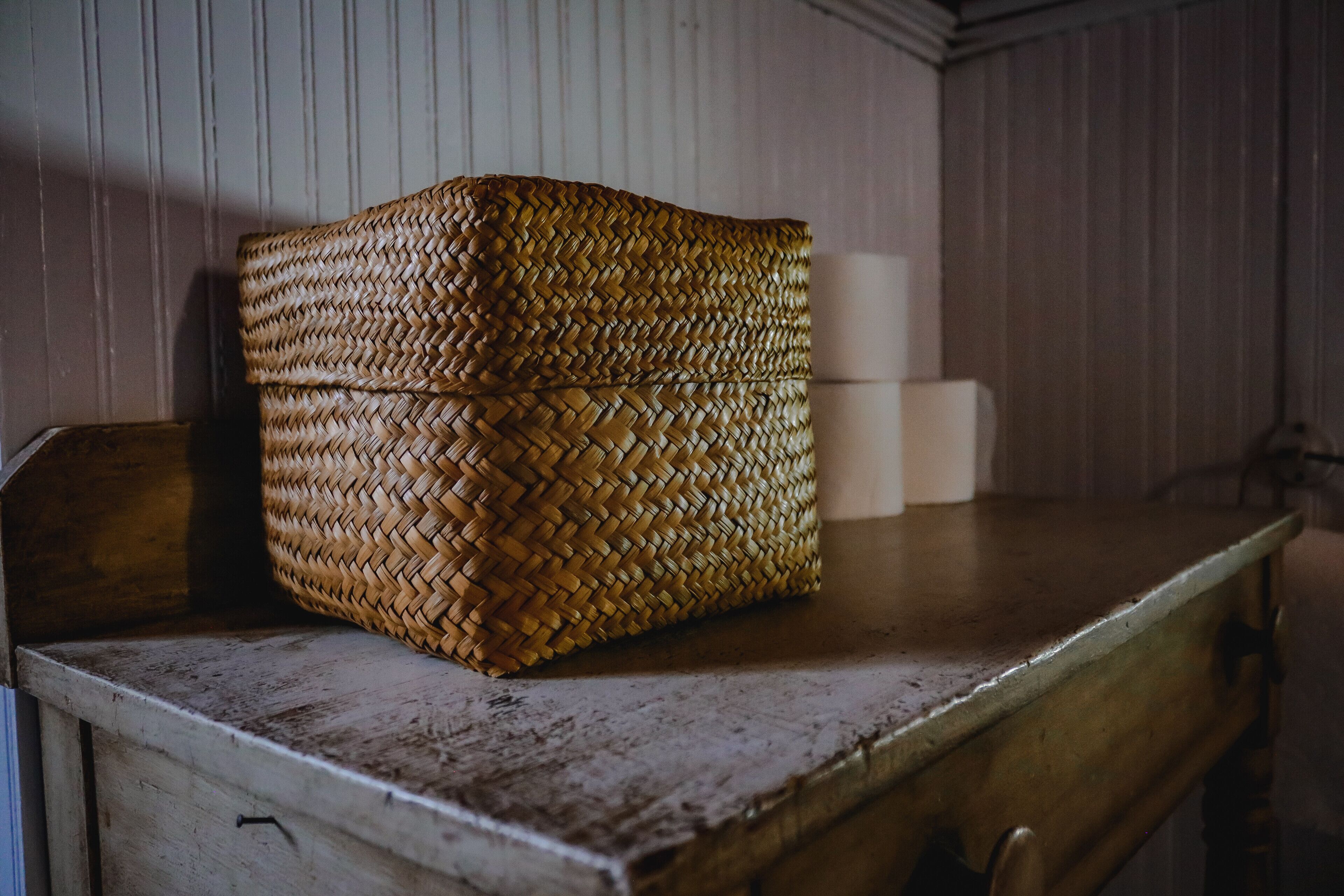 A woven basket on a wooden table with a drawer below.