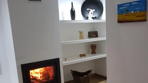 A living room with a fireplace, a black sofa, a white shelf with decorative items, and a painting on the wall. - Villa Terena with private pool (Terena)