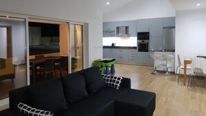 A modern living room with a black sofa, a dining area with a table and chairs, and a kitchen with grey cabinets and appliances. - Villa Terena with private pool (Terena)