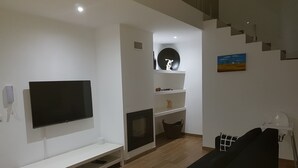 A modern living room with a flat-screen TV, a black sofa, a fireplace, and a staircase. - Villa Terena with private pool (Terena)