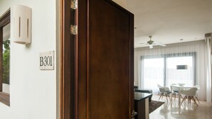 A room with a wooden door, a sign reading "B301", a dining area with a table and chairs, and a ceiling fan. - Mak Nuk Village-1 Bedroom Penthouse-Jacuzzi-Pool (tulum)