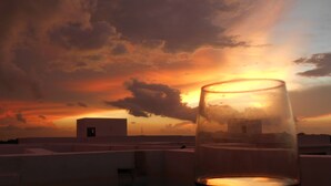A glass of red wine on a table with a sunset view. - Mak Nuk Village-1 Bedroom Penthouse-Jacuzzi-Pool (tulum)