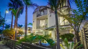 A multi-story hotel with balconies, outdoor seating, and palm trees. - A/C and 3 balconies to enjoy the sun. Beach gear and Traeger included (San Diego)