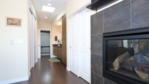 A hallway with a fireplace, a kitchen in the background, and a door leading to another room. - A/C and 3 balconies to enjoy the sun. Beach gear and Traeger included (San Diego)