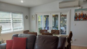 A living room with a brown leather sofa, a blue and white striped rug, and a dining area with a table and chairs. - Private Home great single story home. Plenty of space for the family. (San Diego)