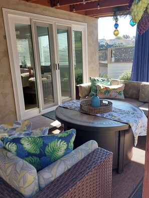 A covered patio area with a round table, wicker furniture, and a view through a glass door. - Private Home great single story home. Plenty of space for the family. (San Diego)
