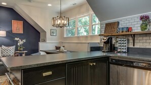 Una cocina moderna con armarios oscuros, lavavajillas de acero inoxidable y encimera negra.