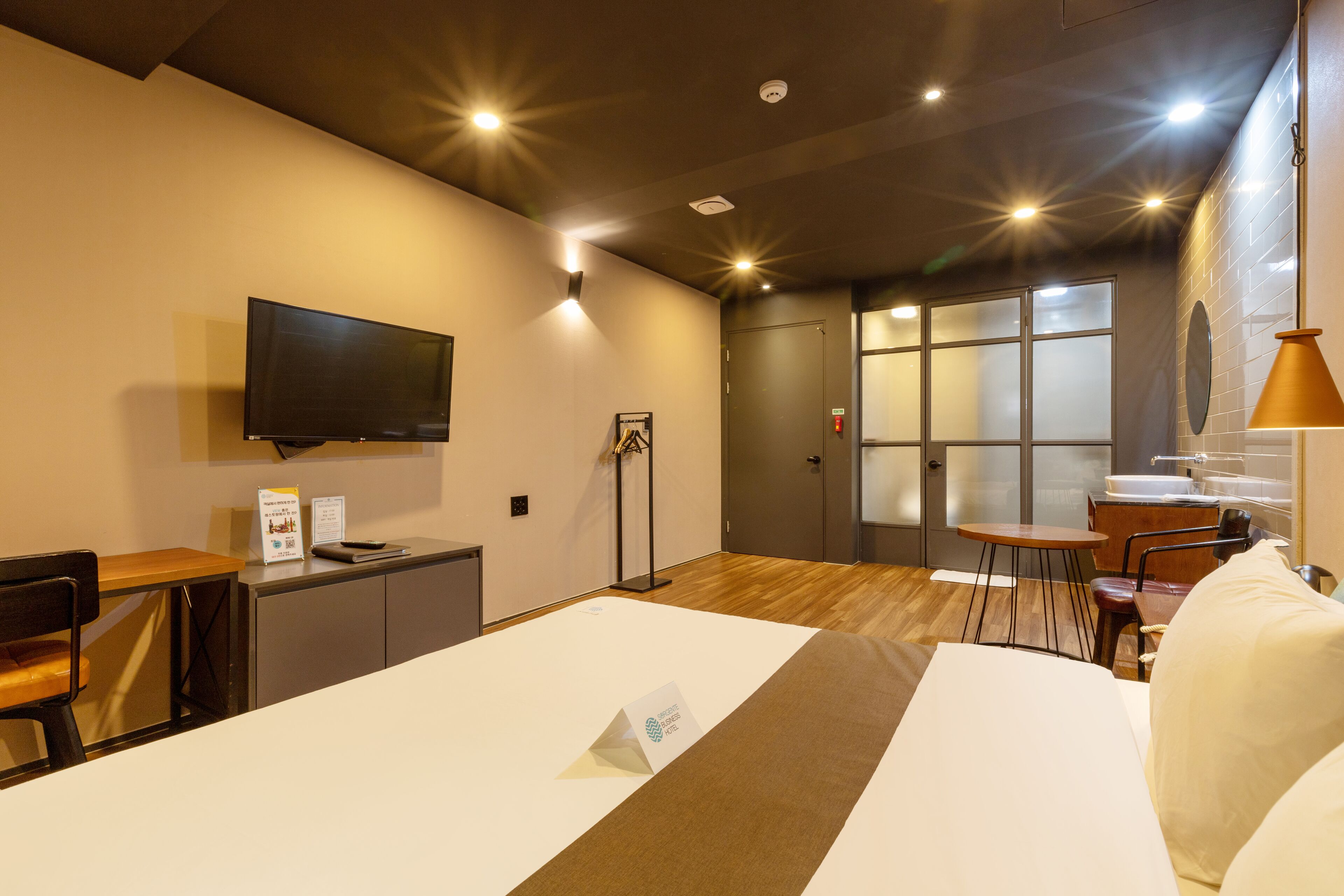Habitación de hotel con cama, escritorio, silla, televisión, mesita y ventana.