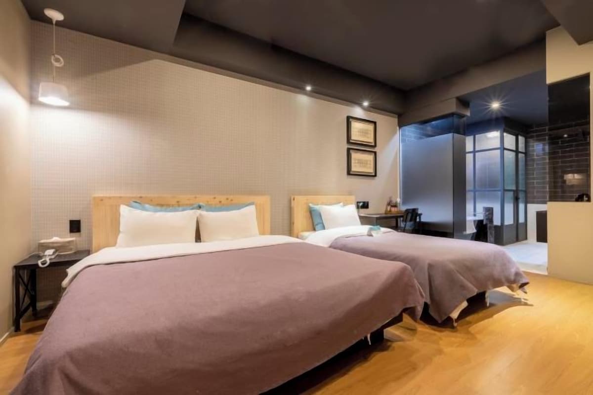 A hotel room with two beds, a small desk, and a view of the city.