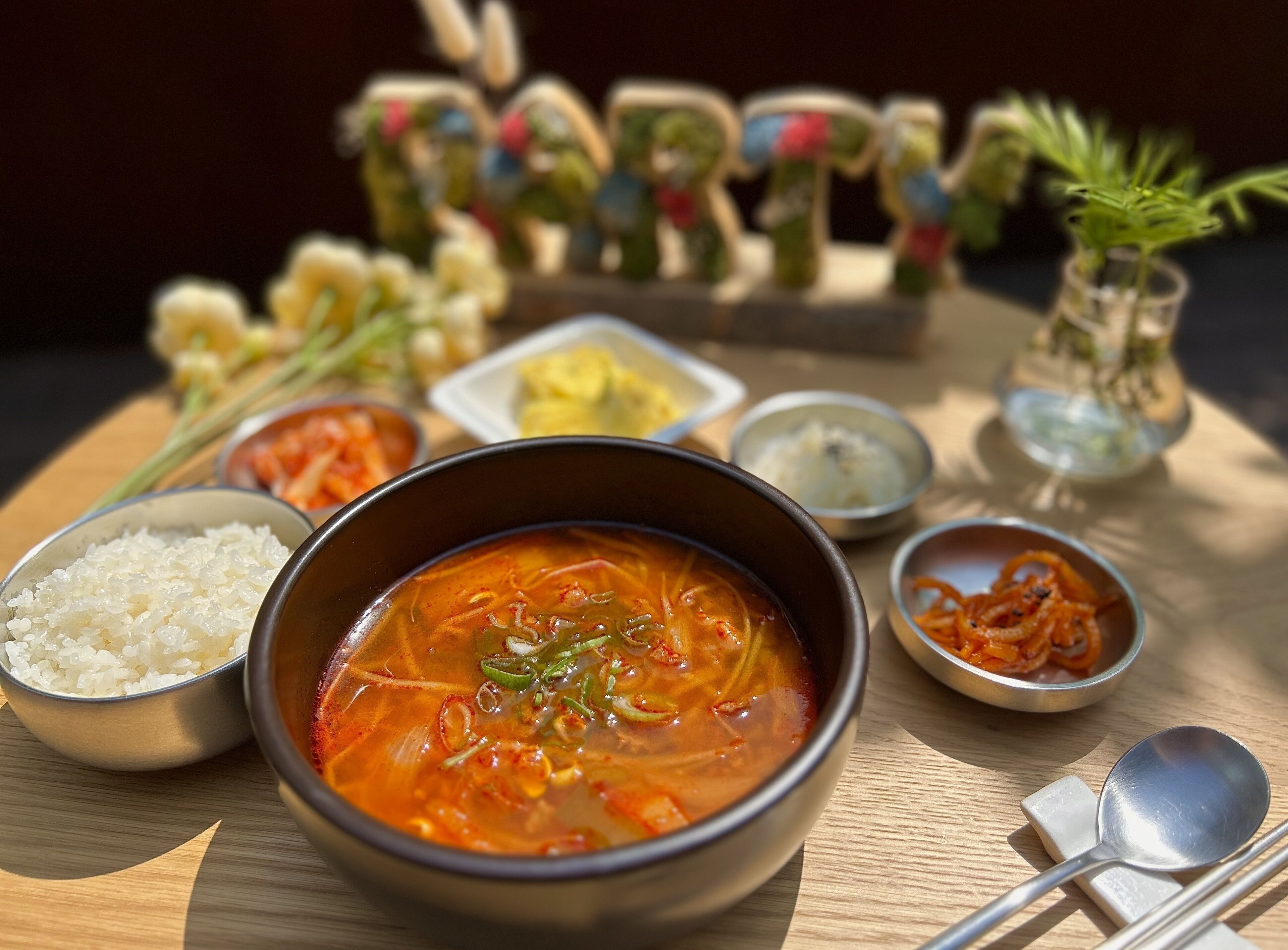 A table with a bowl of soup, rice, and various side dishes.