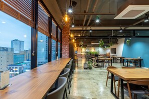 A modern dining area with high ceilings, exposed ductwork, and large windows offering city views. - Sorgente Business Hotel (Busan)