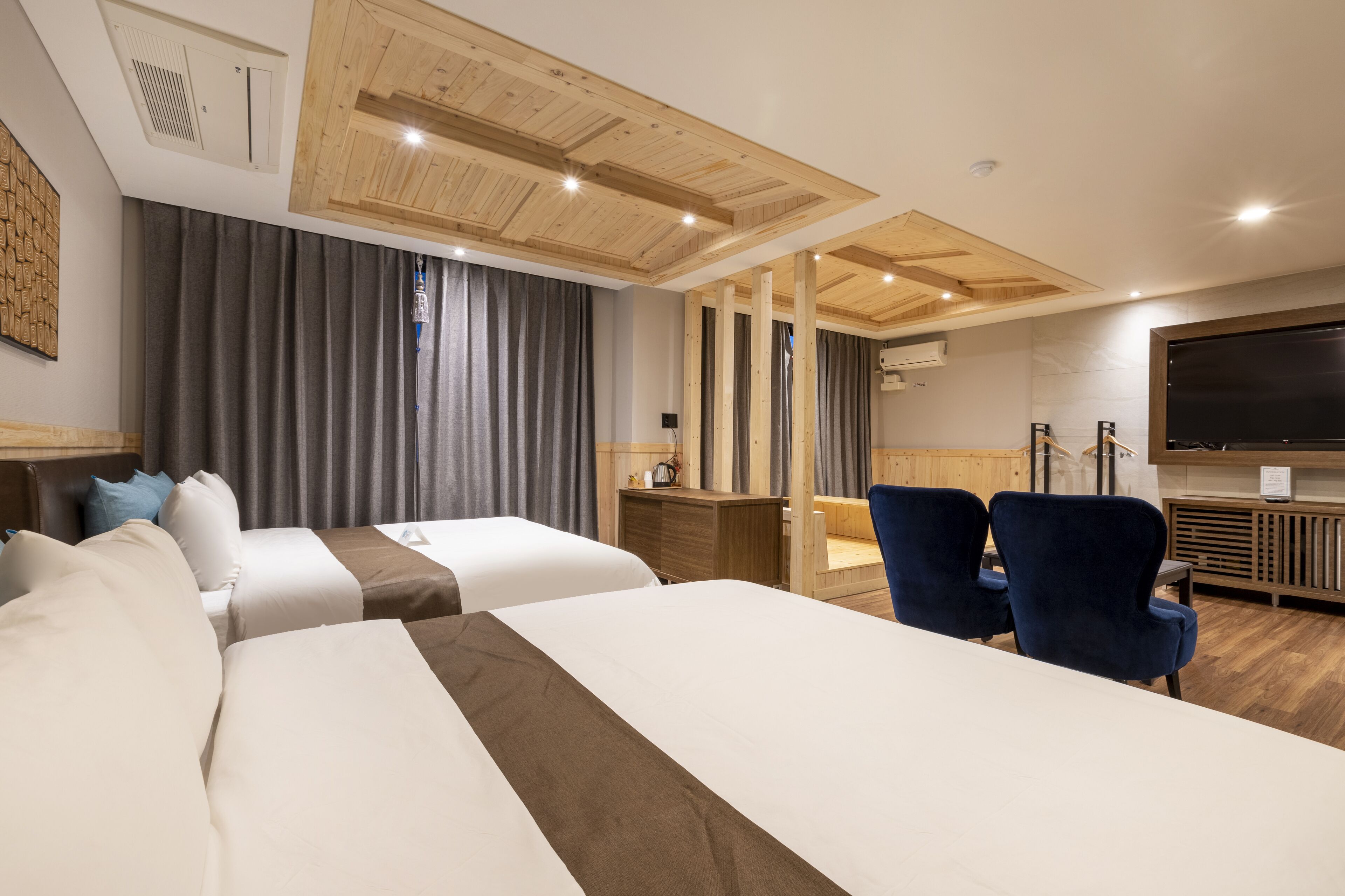 Una habitación de hotel con dos camas, un escritorio, una silla y un televisor.