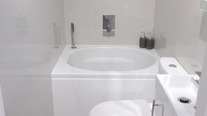A modern bathroom with a freestanding bathtub, a toilet, and a sink. - The studio - the heart of Primrose Hill (London)