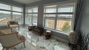 A spacious room with large windows, a ceiling fan, and a marble floor.
