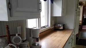 A kitchen with wooden countertops, white cabinets, and a window with curtains. - Very Clean, Well-appointed Cottage (Lakeside Marblehead)