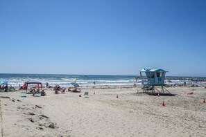 A beach with lifeguard towers, beach chairs, umbrellas, and people relaxing. - Spacious Row Home with Ocean View Roof Deck in the heart of Coastal Oceanside!!  (Oceanside)