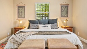 A bedroom with a bed, two bedside tables, a window with blinds, and framed artwork on the walls. - Discover the Perfect Wine Country Getaway 2Bed 2Bath (Paso Robles)