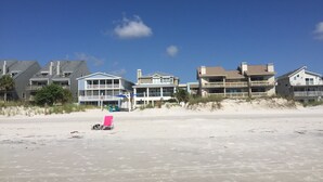 Een strandpand met meerlaagse huizen, een zandstrand en een helderblauwe lucht.