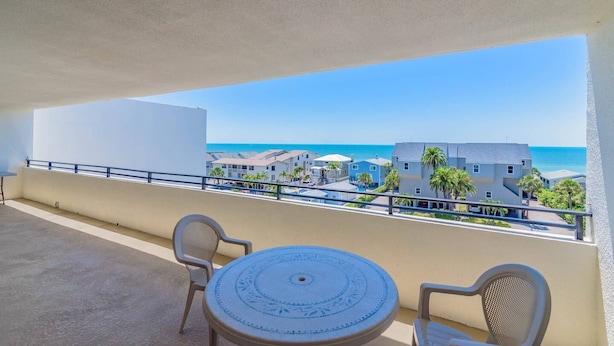Een balkon met uitzicht op het strand en gebouwen.