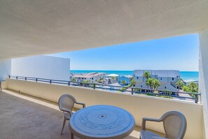 Un balcón con vista a la playa y edificios.