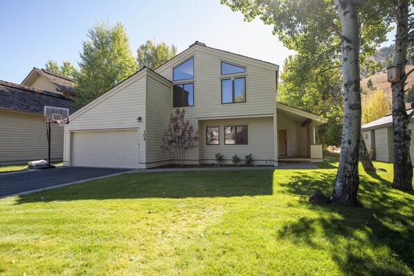 A two-story house with a garage, a basketball hoop, and a well-maintained lawn. - Sunrise Retreat In Sun Valley (Sun Valley)