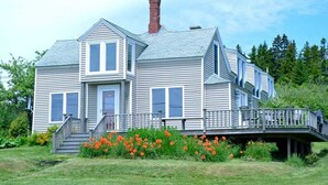 A two-story house with a front porch, a chimney, and a deck.