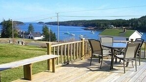 A wooden deck with outdoor seating overlooking a body of water with boats.