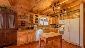 Una cocina tipo cabaña de madera, con armarios de madera, una mesa de madera y un refrigerador.
