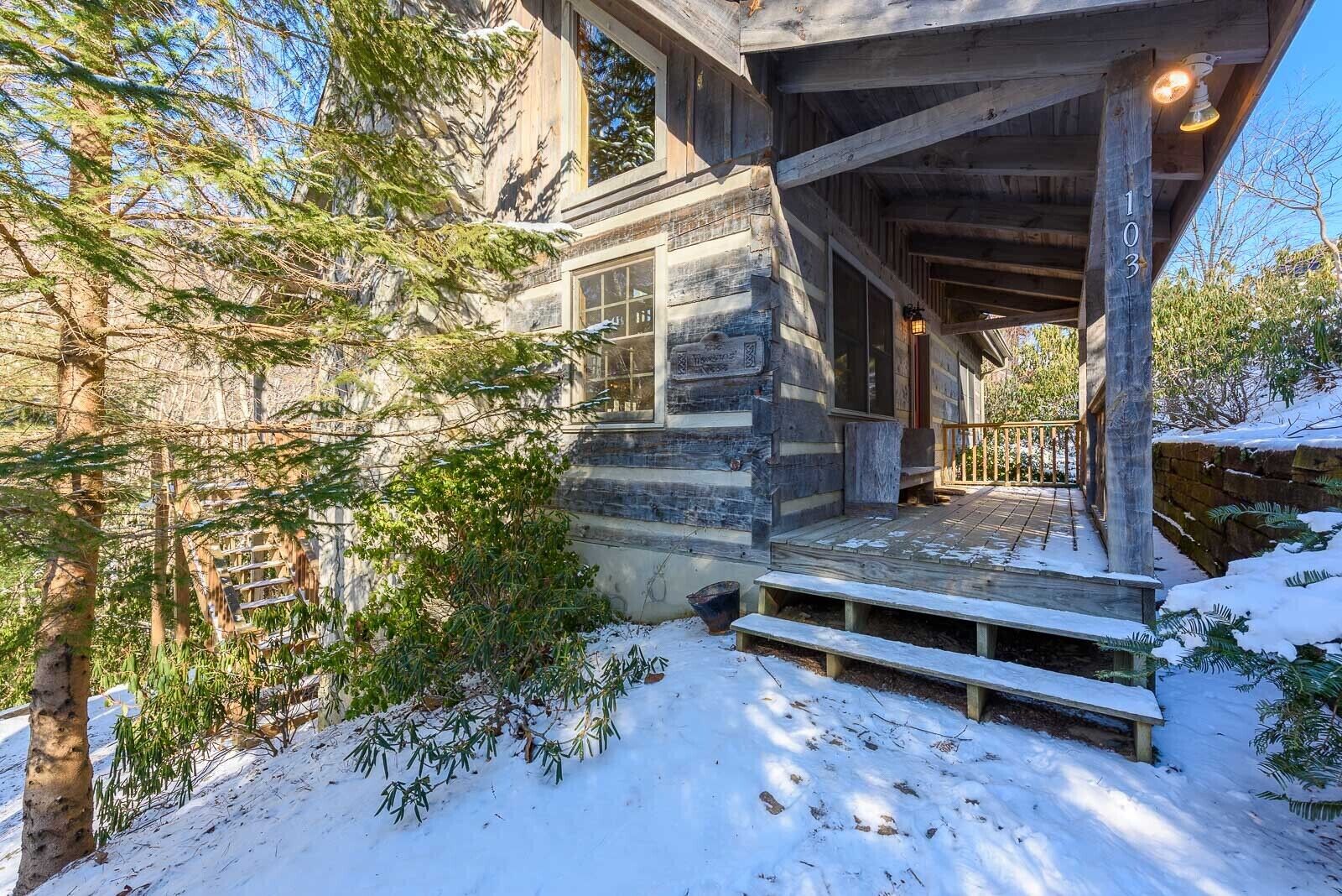 Eine rustikale Holzhütte mit einer hölzernen Veranda, einem Steinfundament und einer schneebedeckten Landschaft.