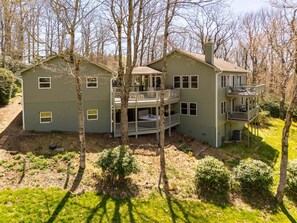 A two-story house with a balcony and a deck, surrounded by trees.