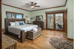 A bedroom with a bed, dresser, nightstand, and a view through a glass door.