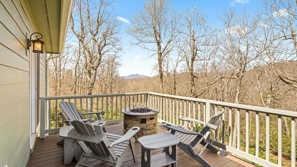 Eine Holzterrasse mit Adirondack-Stühlen und einem Steinkamin.