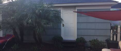 A residential house with a dark roof, a white door, and a covered patio area.