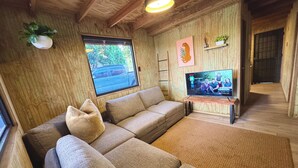 A cozy living room with a large window, a television, and a wooden interior. - Hunter's Cabin PR (Cabo Rojo)