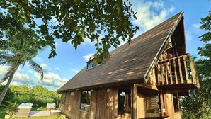 A wooden cabin with a porch, a small deck, and a stone pathway leading to the entrance. - Hunter's Cabin PR (Cabo Rojo)