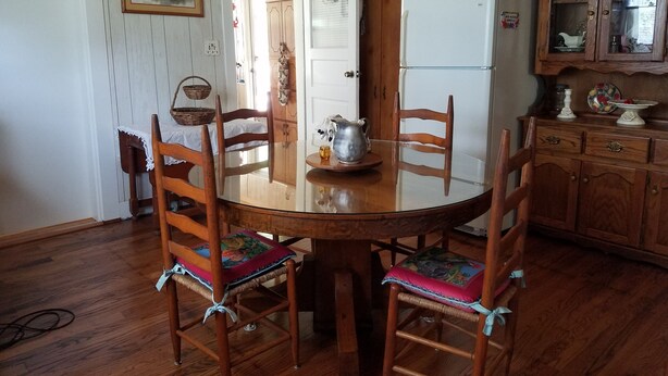 A wooden dining table with chairs, a refrigerator, and a cabinet with glass doors. -  A cozy cottage located 4 miles from Leiper's Fork in Williamson County TN (Thompson's Station)