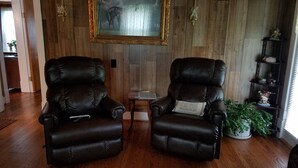 A room with two leather recliners, a wooden paneled wall, a framed painting, a small table with a book, and a potted plant. -  A cozy cottage located 4 miles from Leiper's Fork in Williamson County TN (Thompson's Station)