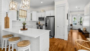 A modern kitchen with white cabinetry, stainless steel appliances, and a central island with stools.