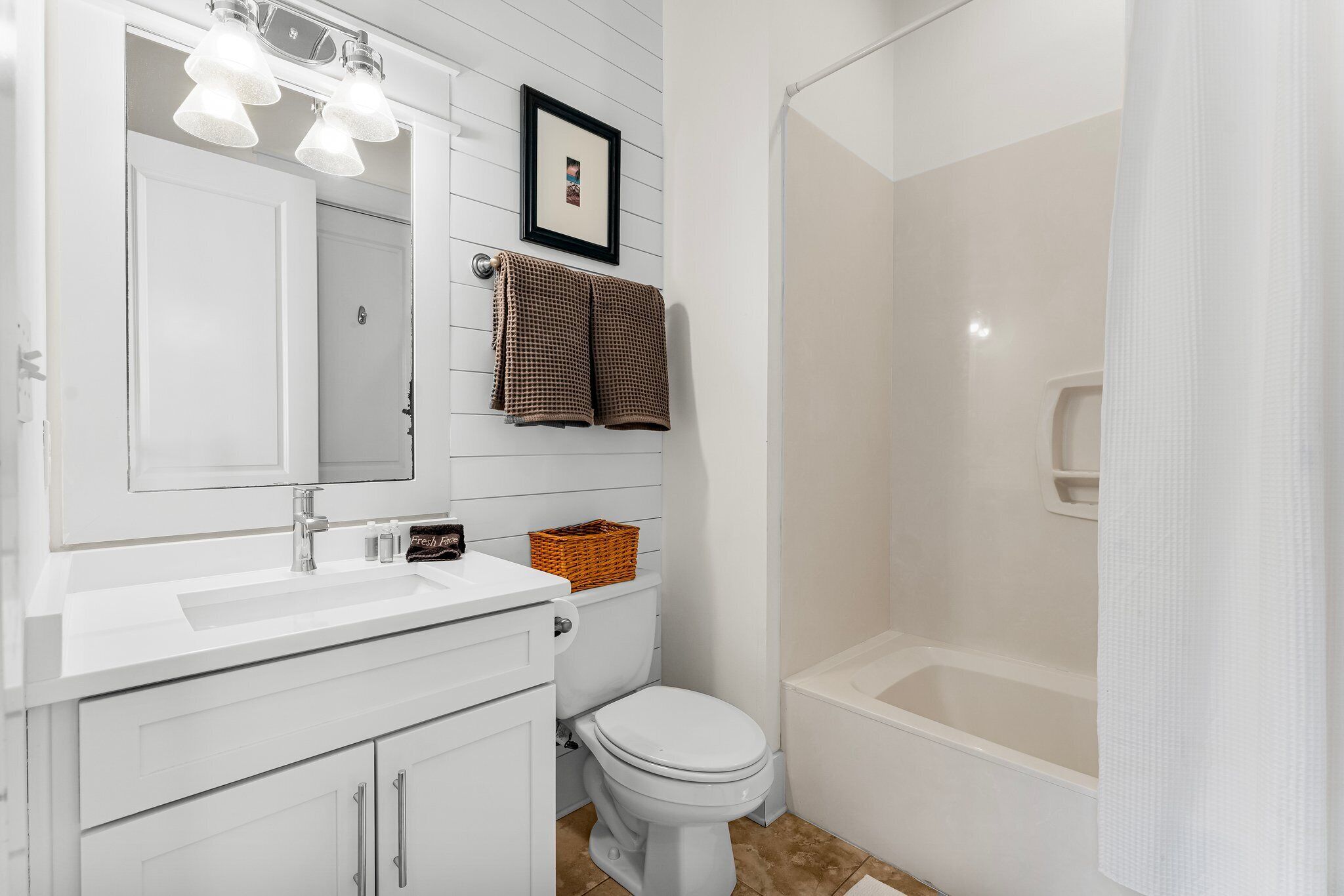 A bathroom with a white vanity, a toilet, and a bathtub.