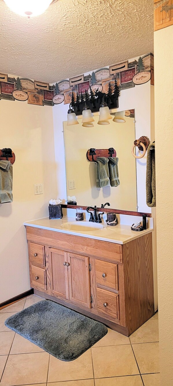 A bathroom with a wooden vanity, a large mirror, and a wall-mounted towel rack.