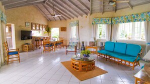 Un vaste espace de vie comprenant un coin repas, un canapé et un ventilateur de plafond.