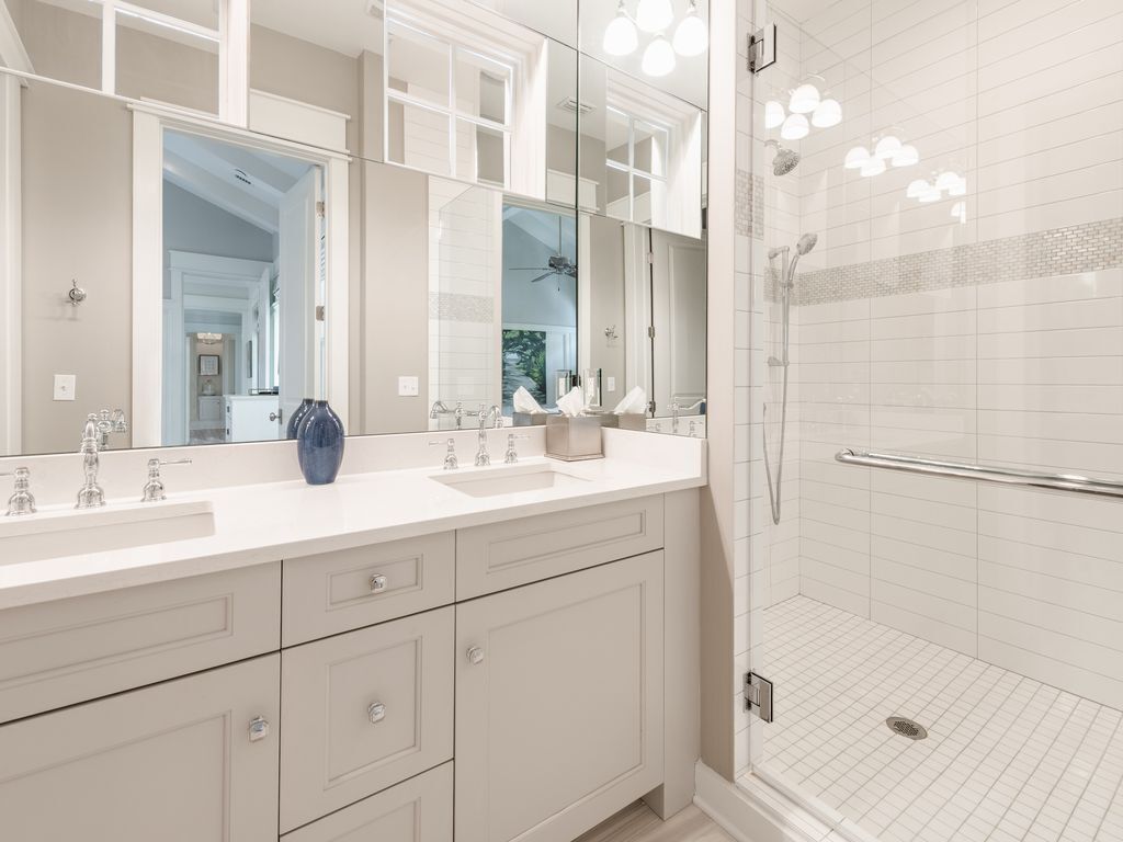 Un baño moderno con un espejo grande, dos lavamanos, una ducha y una zona de ducha a ras de suelo.